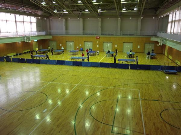 体育館の奥の方に沢山の卓球台が設置され練習している写真